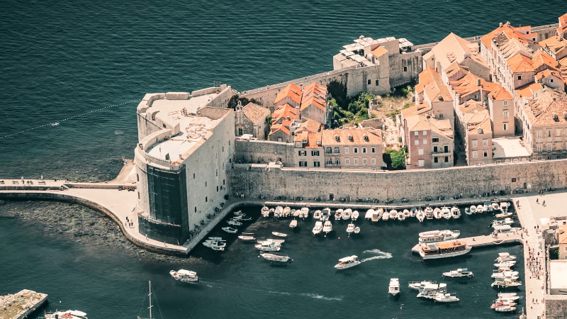 Dubrovnik’s ancient stone walls with a harbor full of boats on the Adriatic Sea
